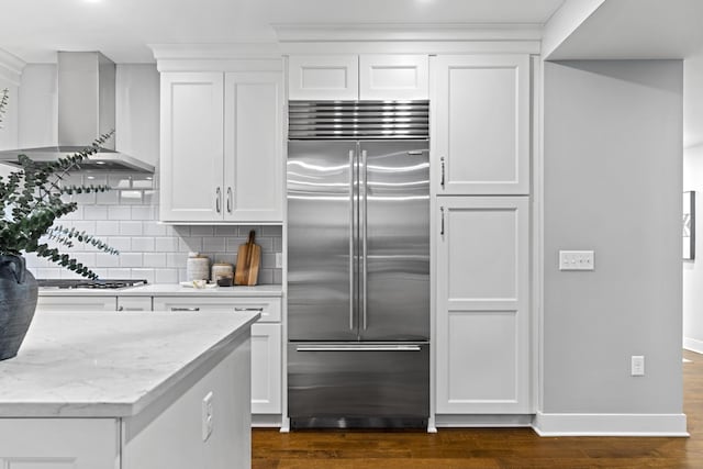 105 N Riverview St Unit 218, Dublin, OH 43017 - kitchen featuring stainless steel built in refrigerator, wall chimney range hood, dark wood-style flooring, tasteful backsplash, and white cabinets