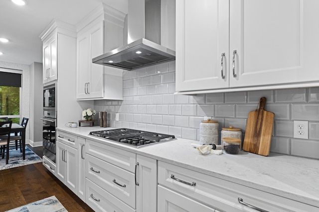 105 N Riverview St Unit 218, Dublin, OH 43017 - kitchen featuring wall chimney exhaust hood, appliances with stainless steel finishes, light stone countertops, white cabinets, and dark wood-type flooring