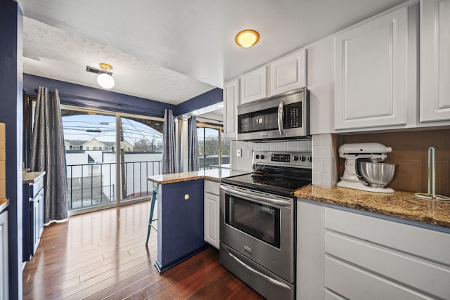 1208 Ashland Ave, Columbus, OH 43212 - kitchen with stainless steel appliances, white cabinetry, dark wood-style flooring, backsplash, and light stone countertops