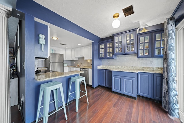 1208 Ashland Ave, Columbus, OH 43212 - kitchen with stainless steel appliances, a peninsula, backsplash, dark wood finished floors, and a breakfast bar area