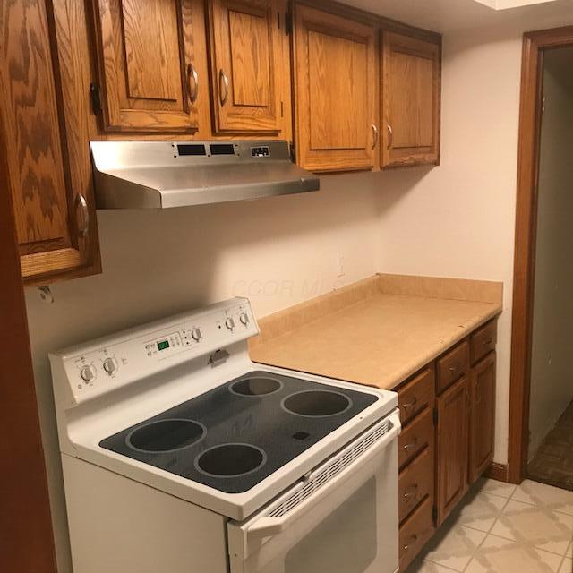 1395 Lake Shore Dr Unit 122, Columbus, OH 43204 - kitchen with electric stove, under cabinet range hood, brown cabinets, and light countertops