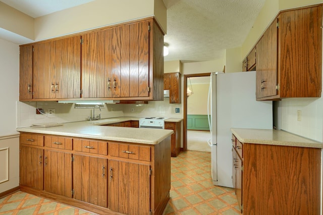 8899 Chevington Ct, Pickerington, OH 43147 - kitchen with light flooring, freestanding refrigerator, a peninsula, brown cabinets, and a textured ceiling