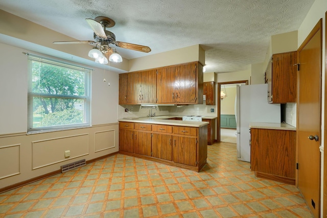 8899 Chevington Ct, Pickerington, OH 43147 - kitchen featuring brown cabinets, freestanding refrigerator, light countertops, light floors, and wainscoting