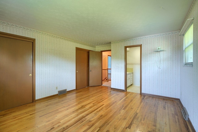 8899 Chevington Ct, Pickerington, OH 43147 - unfurnished bedroom with light wood-style flooring, two closets, wallpapered walls, and connected bathroom