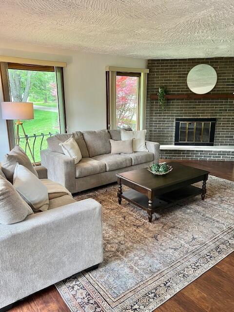 171 Ginder Rd NE, Lancaster, OH 43130 - living area with wood finished floors, healthy amount of natural light, a textured ceiling, and a brick fireplace