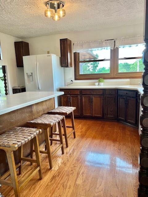 171 Ginder Rd NE, Lancaster, OH 43130 - kitchen with white fridge with ice dispenser, light wood-style floors, light countertops, a textured ceiling, and dark brown cabinetry