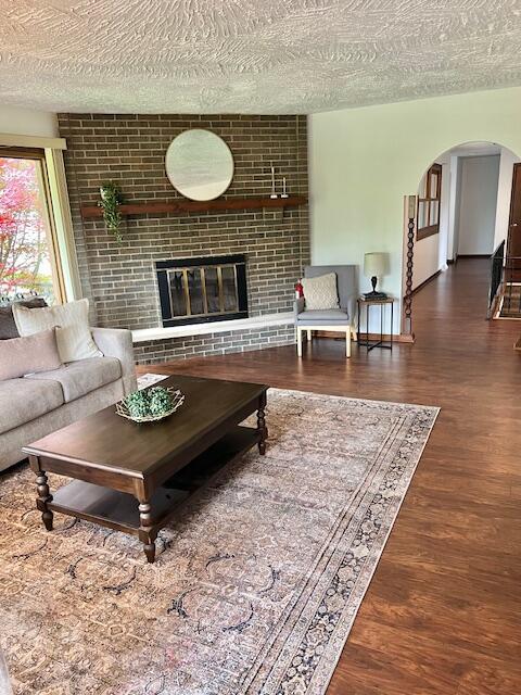 171 Ginder Rd NE, Lancaster, OH 43130 - living room featuring wood finished floors, arched walkways, a textured ceiling, and a brick fireplace