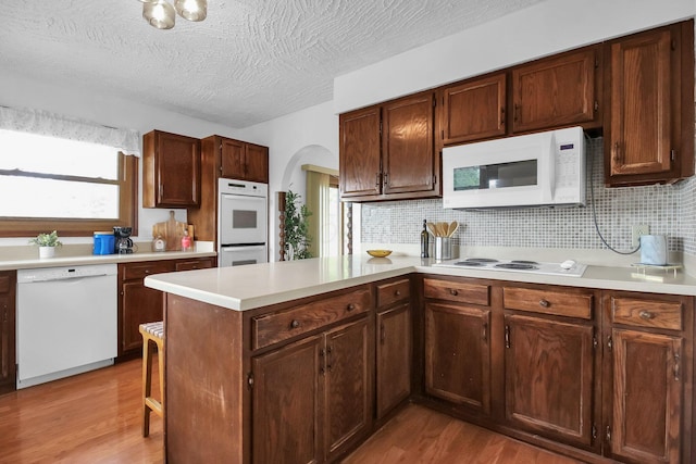 171 Ginder Rd NE, Lancaster, OH 43130 - kitchen featuring white appliances, arched walkways, wood finished floors, light countertops, and backsplash