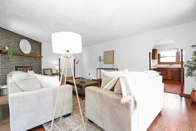171 Ginder Rd NE, Lancaster, OH 43130 - living area featuring wood finished floors, arched walkways, a brick fireplace, and a textured ceiling