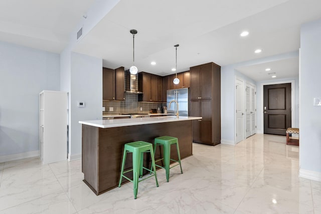 50 W Broad St Unit 3401, Columbus, OH 43215 - kitchen featuring wall chimney range hood, light marble finish flooring, light countertops, a kitchen island with sink, and decorative backsplash
