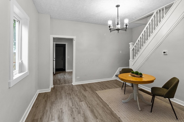 508 E Welch Ave, Columbus, OH 43207 - dining space with wood finished floors, stairs, a chandelier, and a textured ceiling