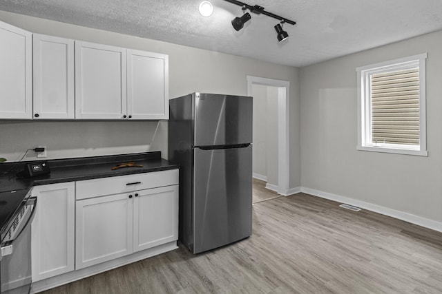 508 E Welch Ave, Columbus, OH 43207 - kitchen featuring appliances with stainless steel finishes, light wood-style flooring, dark countertops, white cabinets, and a textured ceiling