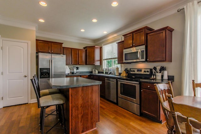 9065 Strawser St, Orient, OH 43146 - kitchen with stainless steel appliances, dark countertops, a kitchen island, wood finished floors, and a kitchen breakfast bar