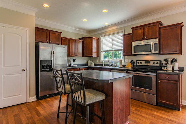 9065 Strawser St, Orient, OH 43146 - kitchen featuring stainless steel appliances, dark countertops, dark wood-style floors, a kitchen bar, and ornamental molding