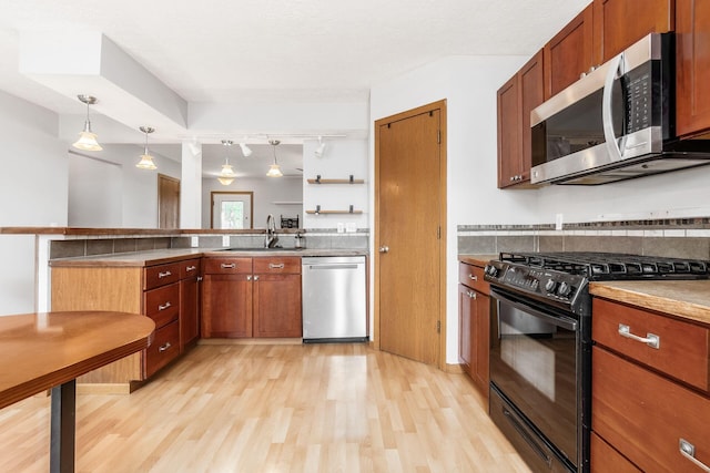 277 Plum Run Ct, Commercial Point, OH 43116 - kitchen featuring stainless steel appliances, light wood finished floors, a peninsula, rail lighting, and hanging light fixtures