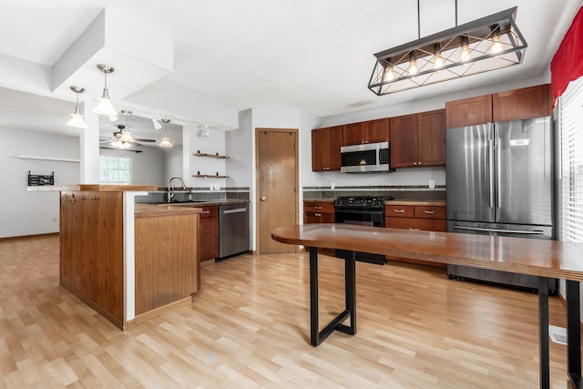 277 Plum Run Ct, Commercial Point, OH 43116 - kitchen featuring appliances with stainless steel finishes, a peninsula, light wood finished floors, and hanging light fixtures