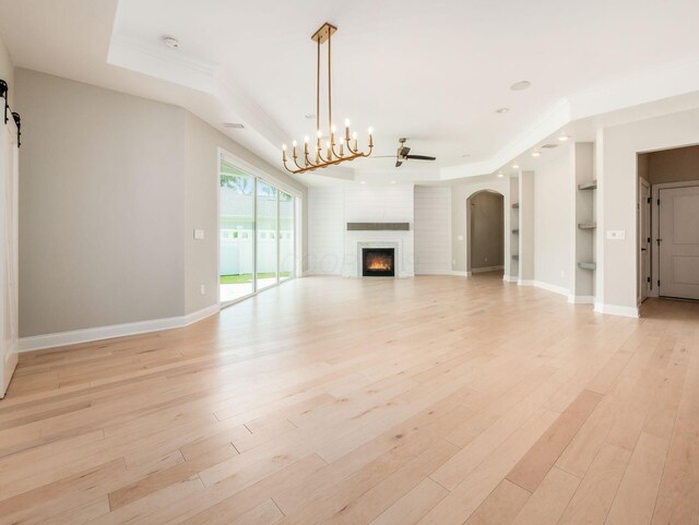 3311 Polden Hill Dr Unit 24, New Albany, OH 43054 - unfurnished living room with a lit fireplace, a tray ceiling, light wood-style floors, built in features, and a chandelier
