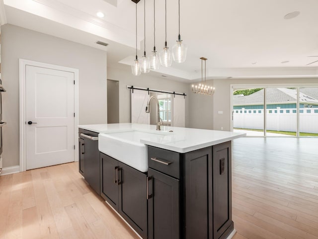 3311 Polden Hill Dr Unit 24, New Albany, OH 43054 - kitchen with a barn door, light wood-style floors, a kitchen island with sink, light countertops, and dishwashing machine