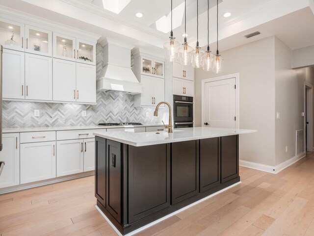 3311 Polden Hill Dr Unit 24, New Albany, OH 43054 - kitchen with black oven, premium range hood, light countertops, an island with sink, and white cabinets