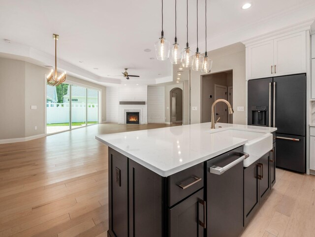 3311 Polden Hill Dr Unit 24, New Albany, OH 43054 - kitchen with high quality fridge, stainless steel dishwasher, ceiling fan, a warm lit fireplace, and a center island with sink