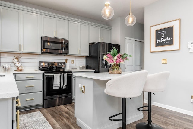 7036 Cannon Dr, Canal Winchester, OH 43110 - kitchen featuring stainless steel appliances, dark wood finished floors, tasteful backsplash, and a breakfast bar