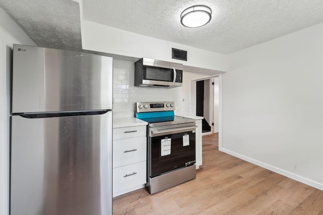 1366 Brown Rd, Columbus, OH 43223 - kitchen with appliances with stainless steel finishes, a textured ceiling, light countertops, white cabinetry, and light wood-type flooring