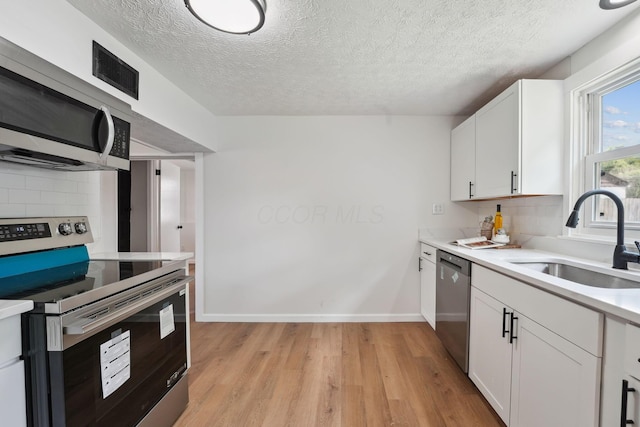 1366 Brown Rd, Columbus, OH 43223 - kitchen with appliances with stainless steel finishes, decorative backsplash, light wood-style flooring, light countertops, and white cabinetry