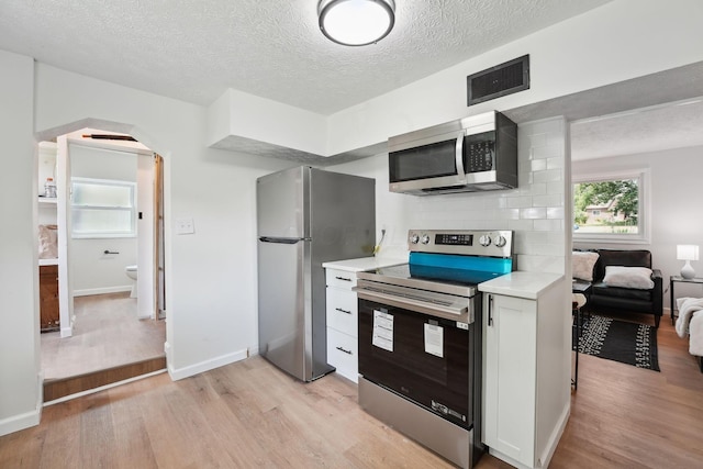 1366 Brown Rd, Columbus, OH 43223 - kitchen with stainless steel appliances, light wood-style floors, light countertops, white cabinetry, and a textured ceiling