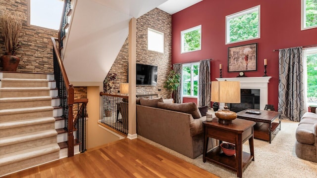 8933 Winding Creek Way, Pickerington, OH 43147 - living area featuring a glass covered fireplace, wood finished floors, a high ceiling, and stairs