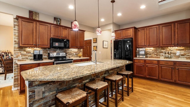 8933 Winding Creek Way, Pickerington, OH 43147 - kitchen with black appliances, light wood-style flooring, backsplash, a kitchen breakfast bar, and recessed lighting