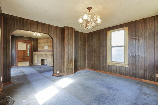 141 W Waterloo St, Canal Winchester, OH 43110 - empty room featuring carpet, a chandelier, arched walkways, a fireplace, and wooden walls