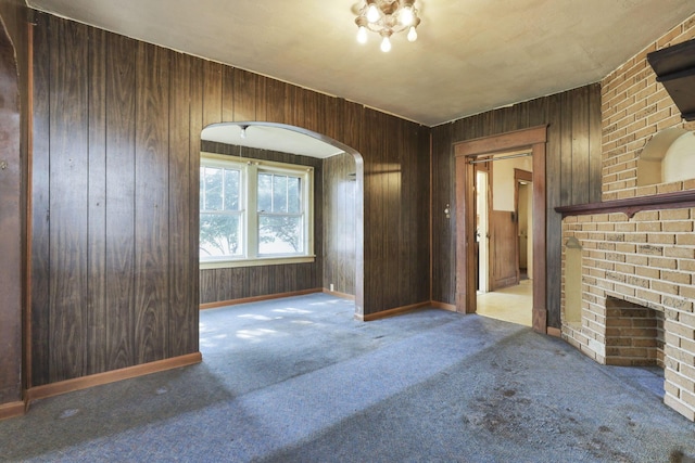 141 W Waterloo St, Canal Winchester, OH 43110 - unfurnished living room featuring carpet floors, arched walkways, wood walls, and a fireplace
