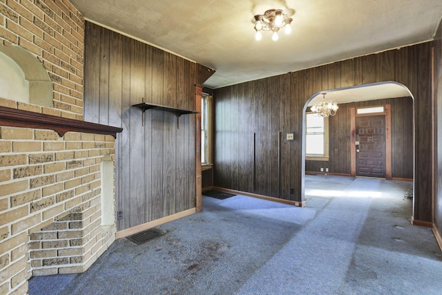 141 W Waterloo St, Canal Winchester, OH 43110 - unfurnished living room featuring a chandelier, arched walkways, carpet flooring, and wooden walls