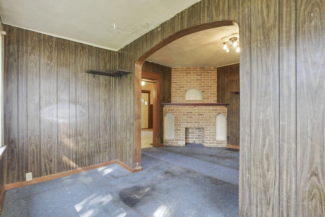 141 W Waterloo St, Canal Winchester, OH 43110 - unfurnished living room featuring wood walls, carpet floors, arched walkways, and a fireplace