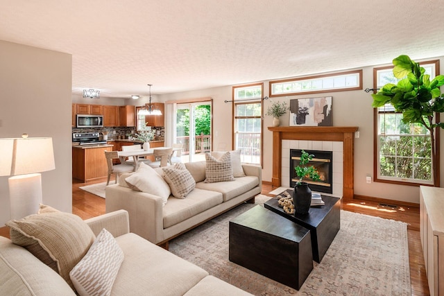 2378 Yagger Bay Dr, Hilliard, OH 43026 - living room with light wood-style flooring, a textured ceiling, a tiled fireplace, and a chandelier