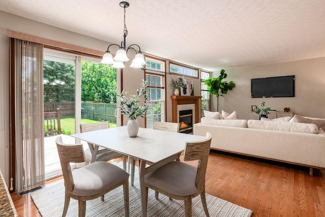 2378 Yagger Bay Dr, Hilliard, OH 43026 - dining space featuring a textured ceiling, a chandelier, a fireplace, and light wood-style floors