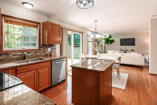2378 Yagger Bay Dr, Hilliard, OH 43026 - kitchen with stainless steel dishwasher, a textured ceiling, a kitchen island, tasteful backsplash, and brown cabinetry