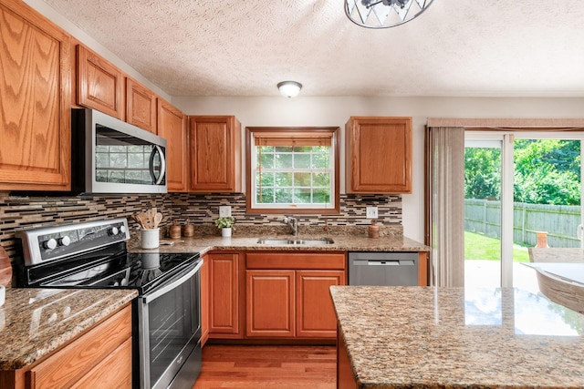 2378 Yagger Bay Dr, Hilliard, OH 43026 - kitchen with stainless steel appliances, decorative backsplash, light wood-type flooring, light stone countertops, and a textured ceiling