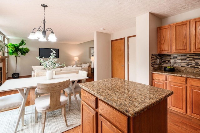 2378 Yagger Bay Dr, Hilliard, OH 43026 - kitchen featuring a center island, decorative backsplash, light wood finished floors, a chandelier, and a textured ceiling