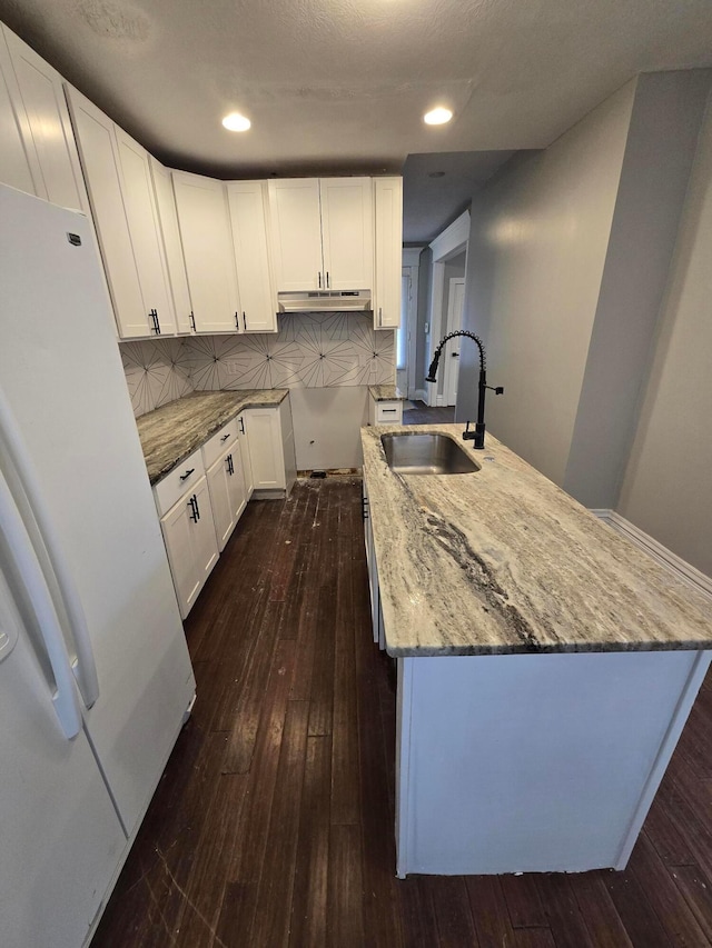 1035 Sullivant Ave, Columbus, OH 43223 - kitchen featuring freestanding refrigerator, light stone counters, dark wood-style floors, tasteful backsplash, and under cabinet range hood
