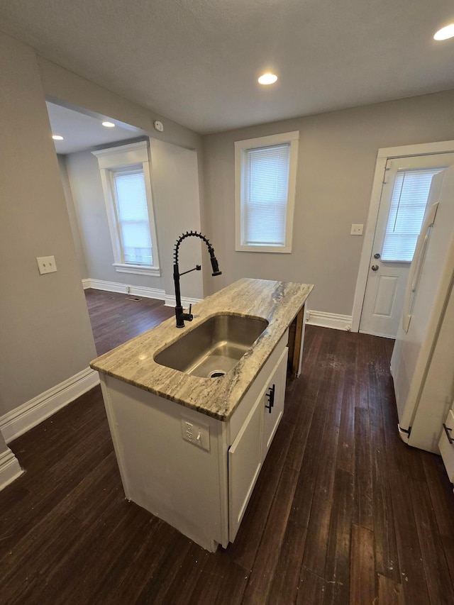 1035 Sullivant Ave, Columbus, OH 43223 - kitchen with light stone countertops, dark wood finished floors, white cabinetry, a kitchen island with sink, and freestanding refrigerator