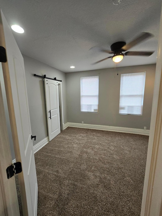 1035 Sullivant Ave, Columbus, OH 43223 - unfurnished bedroom featuring carpet, a barn door, a textured ceiling, and a ceiling fan