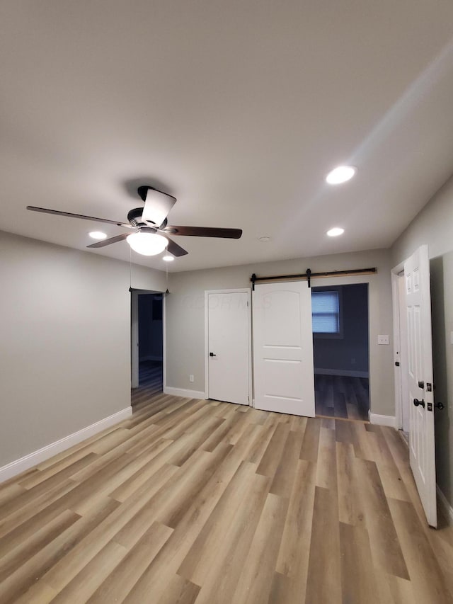 345 Dakota Ave, Columbus, OH 43223 - unfurnished bedroom with a barn door, light wood-style floors, recessed lighting, and a ceiling fan