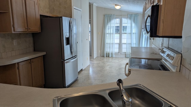 22 Birch Row Dr, Delaware, OH 43015 - kitchen with appliances with stainless steel finishes, vaulted ceiling, light countertops, and brown cabinets