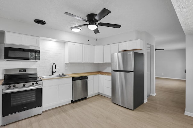 1615 Coronet Dr, Columbus, OH 43224 - kitchen featuring appliances with stainless steel finishes, tasteful backsplash, light wood-type flooring, a textured ceiling, and white cabinets