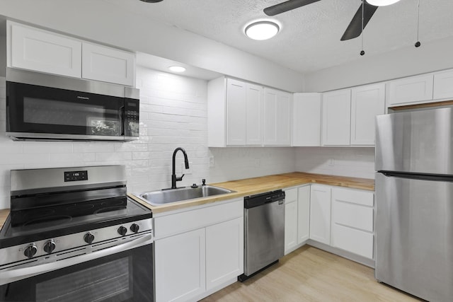 1615 Coronet Dr, Columbus, OH 43224 - kitchen with appliances with stainless steel finishes, backsplash, a ceiling fan, light wood-type flooring, and a textured ceiling