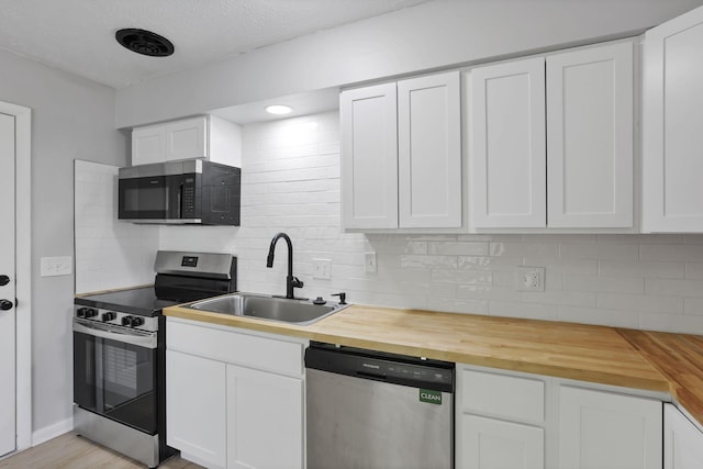 1615 Coronet Dr, Columbus, OH 43224 - kitchen featuring stainless steel appliances, butcher block countertops, tasteful backsplash, and white cabinetry