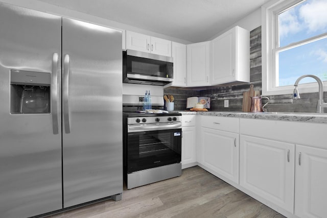 634 Columbus Ave Unit 1, Washington Court House, OH 43160 - kitchen with appliances with stainless steel finishes, white cabinetry, tasteful backsplash, and light wood-style flooring