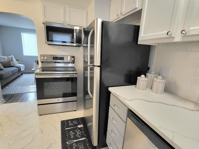 570 N Ohio Ave, Columbus, OH 43203 - kitchen featuring stainless steel appliances, white cabinets, arched walkways, light marble finish floors, and light stone counters