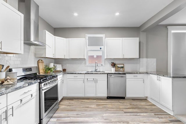225 N Hague Ave, Columbus, OH 43204 - kitchen with stainless steel appliances, wall chimney range hood, white cabinetry, light stone countertops, and recessed lighting